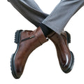 Brown leather boots with zippers worn by a person on a white background