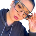 Person wearing a dark hoodie and clear-framed glasses with a blurred background