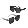 Black sunglasses with decorative frames on a white platform against a light blue background