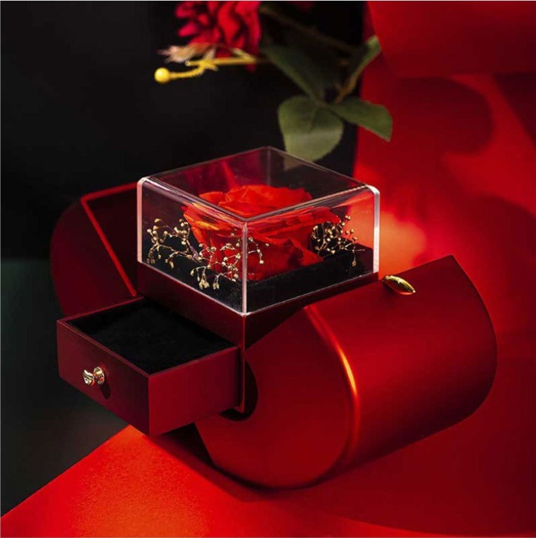Red heart-shaped box with a rose and necklace inside on a white background