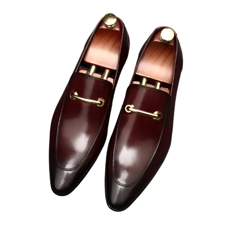 A pair of men's brown cowhide leather dress shoes with toe caps and metal accents on a dark background.