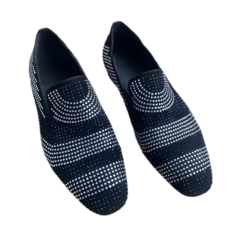 A pair of black and white rhinestone-decorated loafers placed on a wooden surface.
