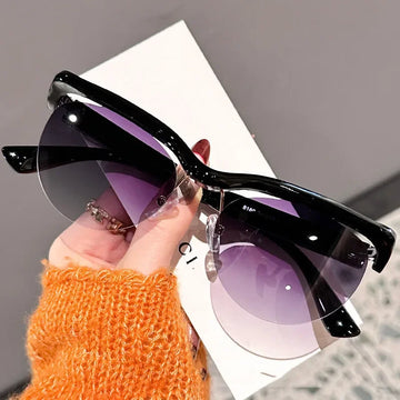 Black sunglasses with purple lenses held by a hand wearing an orange sleeve.