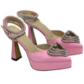 Pink high-heeled shoes with embellishments on a white background