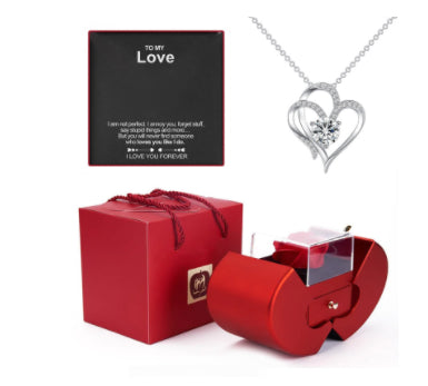 Heart-shaped silver necklace in a red box with a 'Love' card on a white background