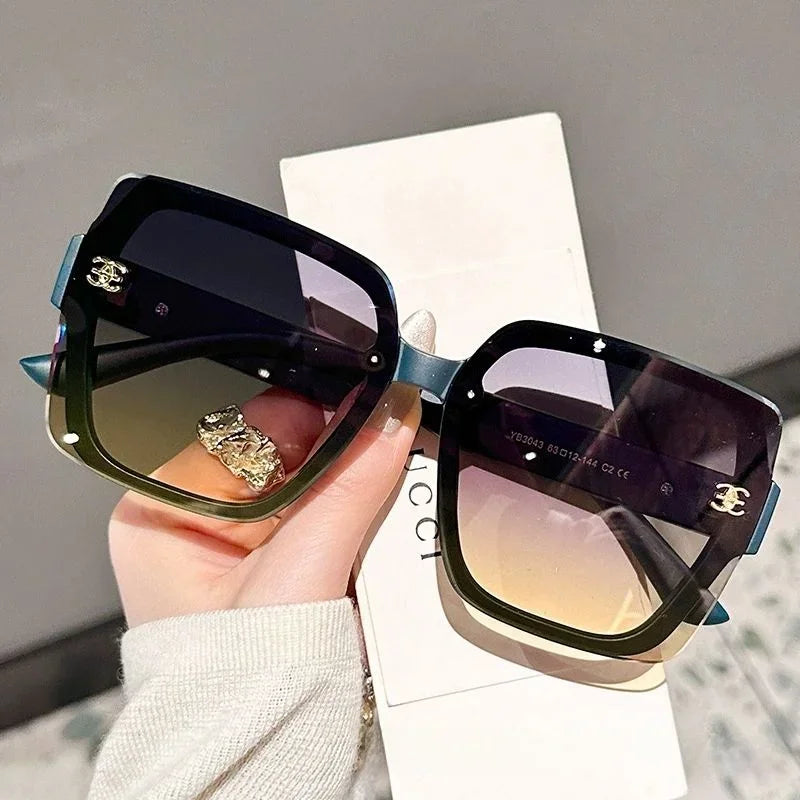 Sunglasses held by a hand with a blurred background