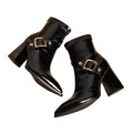 Pair of black high-heeled boots with gold buckles on a white background