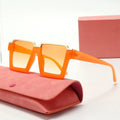 Orange sunglasses with gold accents on a pink case against a white background