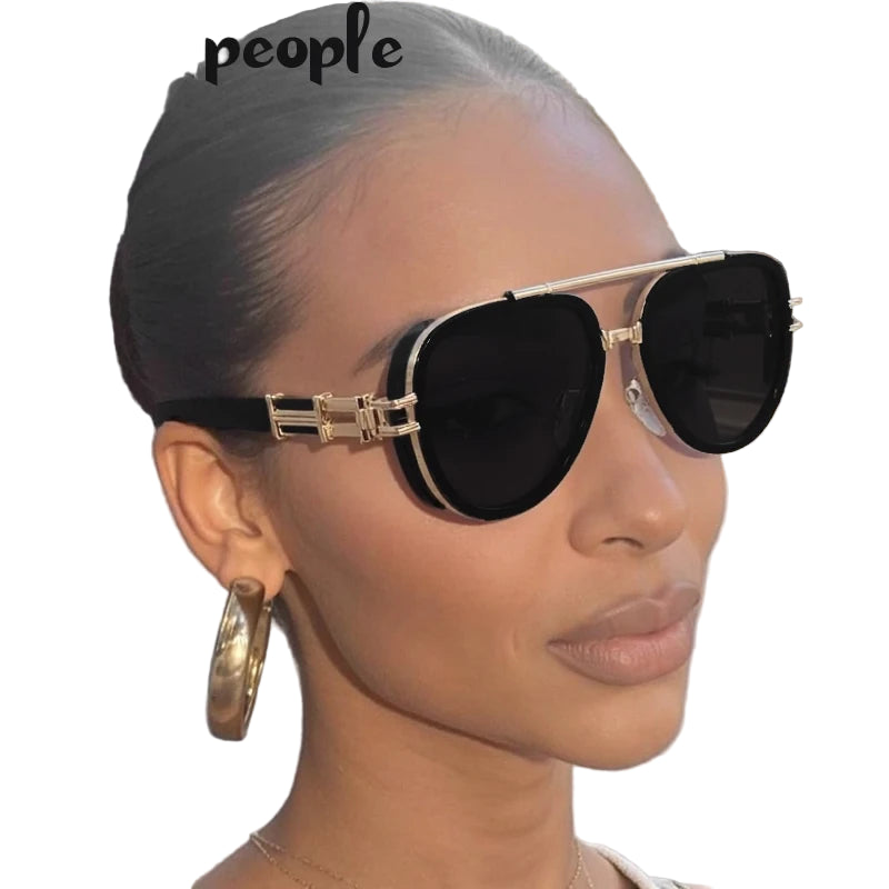 Woman wearing gold-framed sunglasses with a plain background
