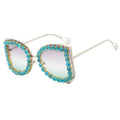 Sunglasses with turquoise and gold embellishments on a white background