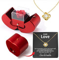 Red gift box with a rose, gold necklace with heart pendant, and black card with text on a white background.