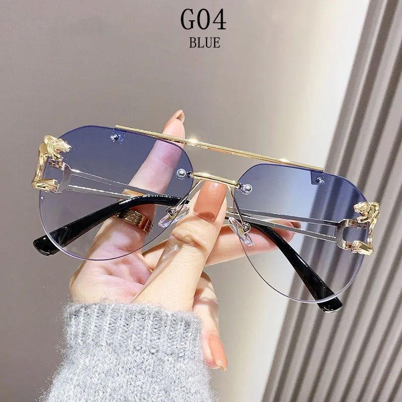 Sunglasses with gold frames and blue lenses held by a hand against a neutral background