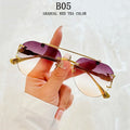 Sunglasses with gold frame and purple gradient lenses held by a hand against a white background.