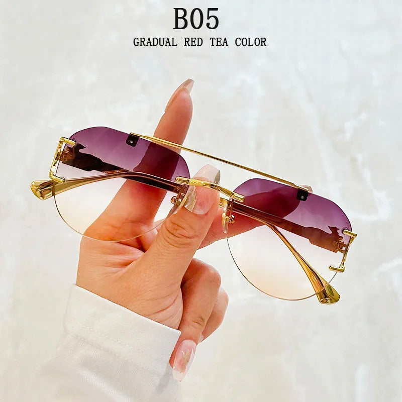 Sunglasses with gold frame and purple gradient lenses held by a hand against a white background.
