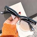Person holding a pair of sunglasses with a blurred background