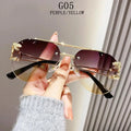 Sunglasses with gold frame and purple lenses held by a hand against a neutral background