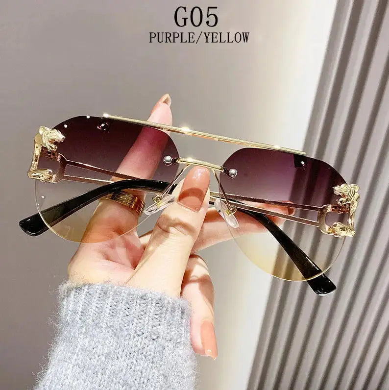 Sunglasses with gold frame and purple lenses held by a hand against a neutral background