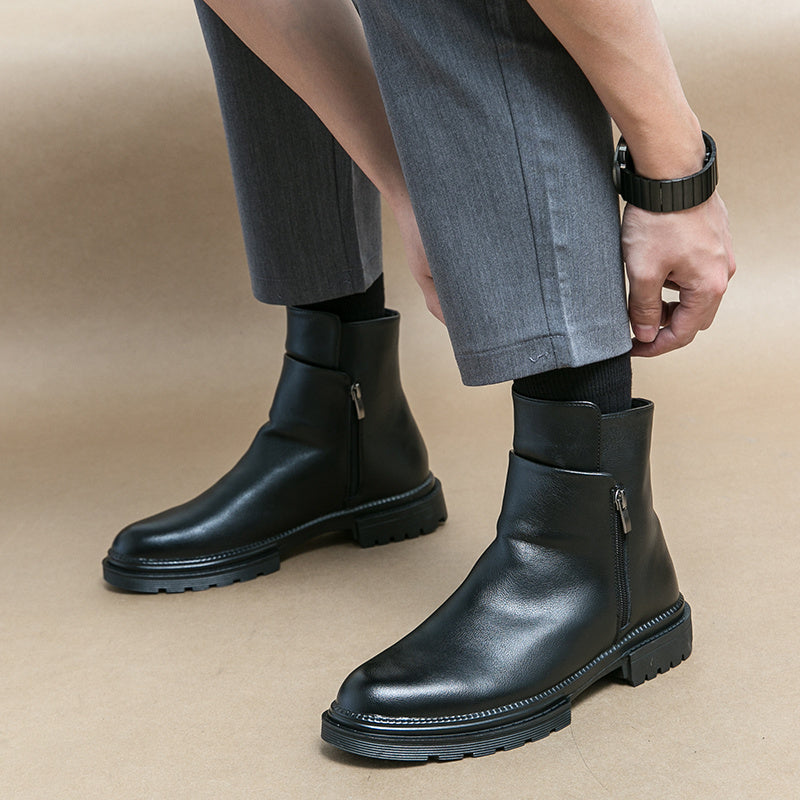 Black leather boots worn with gray pants on a beige background