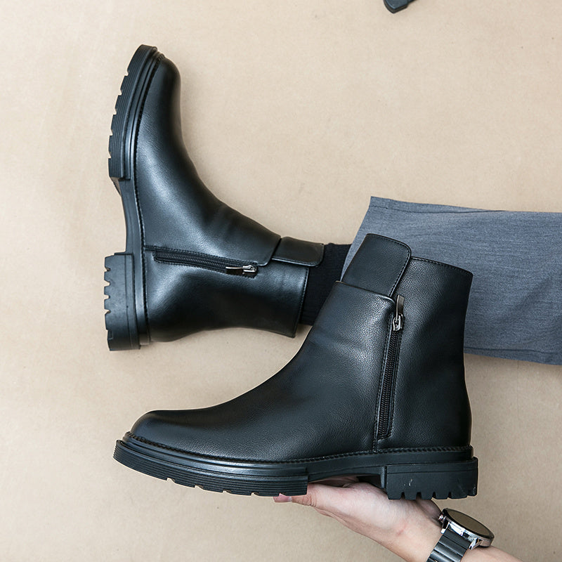 Black leather boots being worn on a beige background