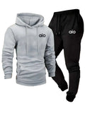 Gray hoodie and black pants with 'aio' logo on a wooden shelf background