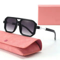 Black sunglasses with gradient lenses on a pink case against a white background