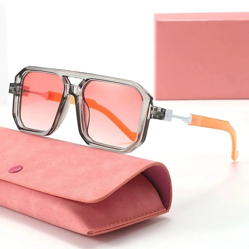 Sunglasses with pink and orange gradient lenses and orange arms on a pink case with a matching box.