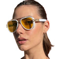 Woman wearing yellow sunglasses with a wooden and red wall background