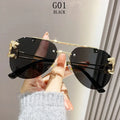 Black sunglasses with gold accents held by a hand against a neutral background