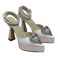 White high-heeled shoes with silver heart embellishments on a light background