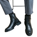Black leather boots worn with gray pants on a white background