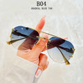 Sunglasses with gold frame and blue gradient lenses held by a hand against a light background