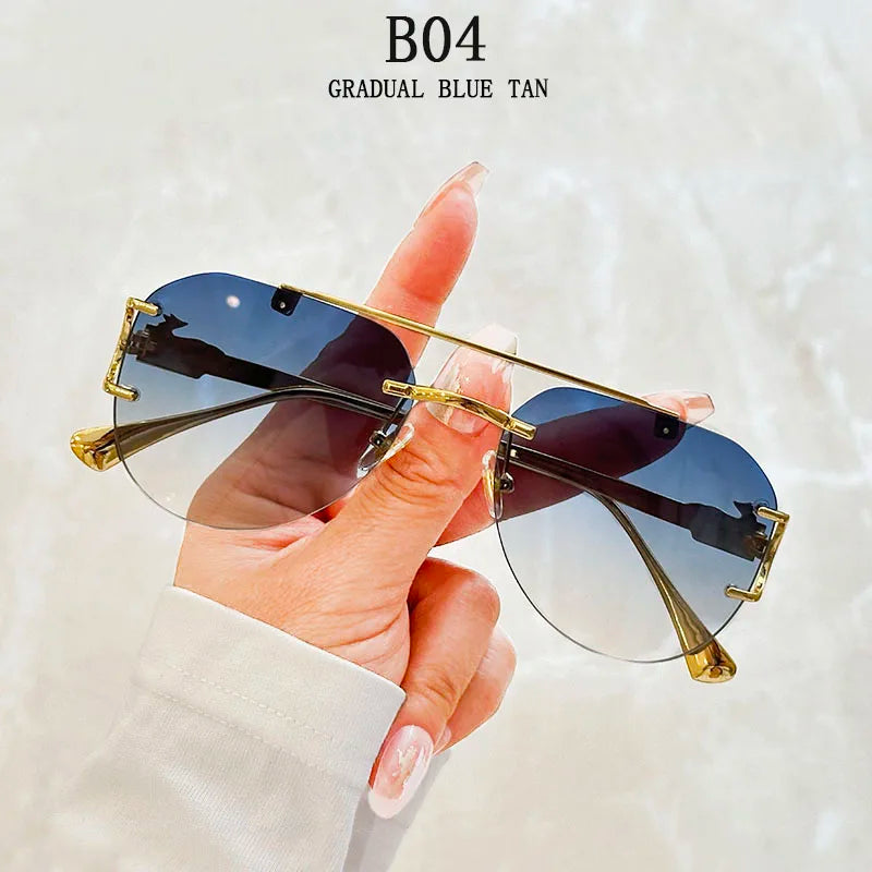Sunglasses with gold frame and blue gradient lenses held by a hand against a light background