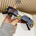 Sunglasses with gold accents held by a hand against a neutral background