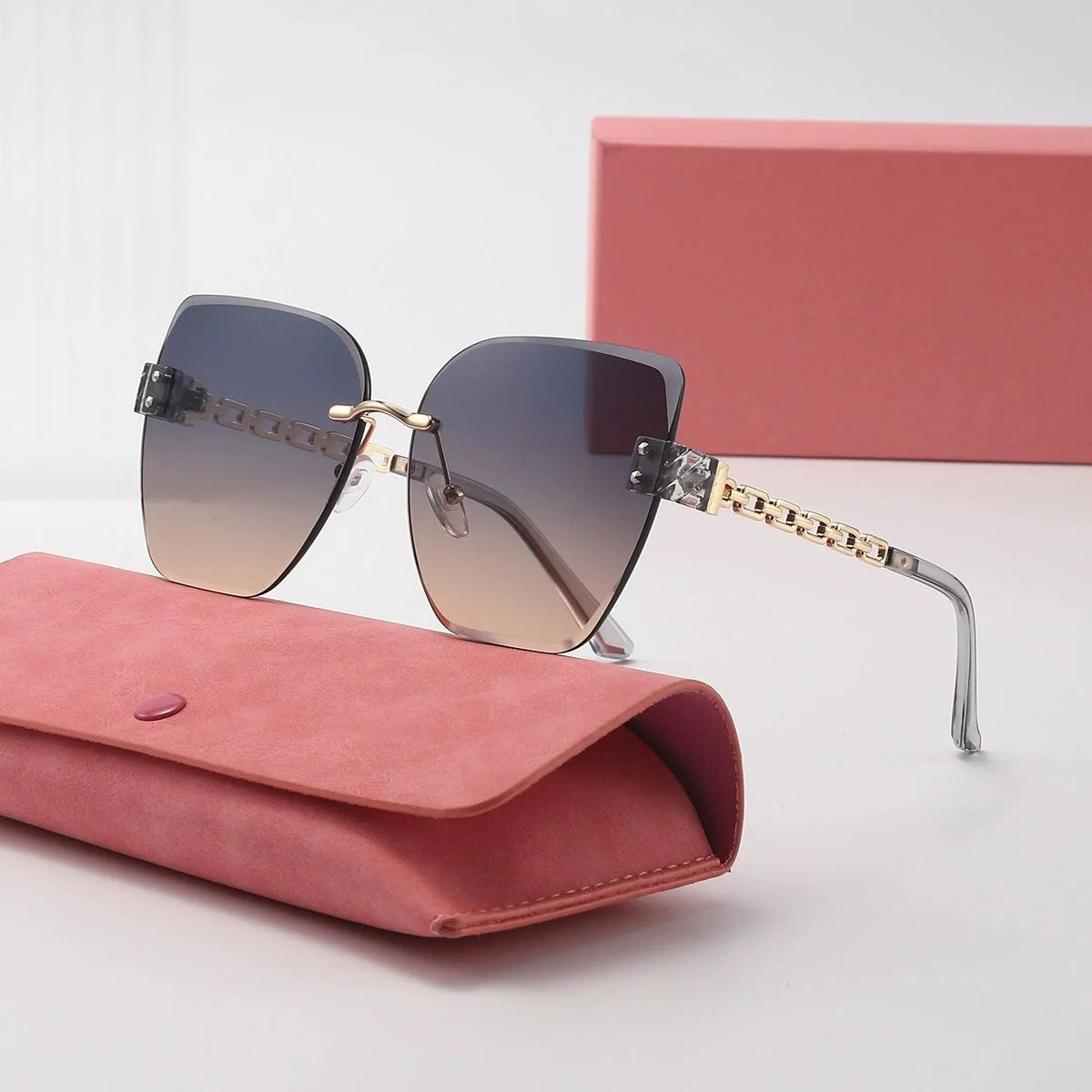 Sunglasses with gold accents on a pink case with a pink box in the background
