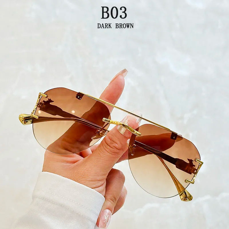 Sunglasses with gold frame and dark brown lenses held by a hand against a light background