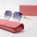 Sunglasses with gradient lenses and gold accents on a pink case with a matching box in the background.