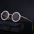 Round sunglasses with gold frame on a dark background