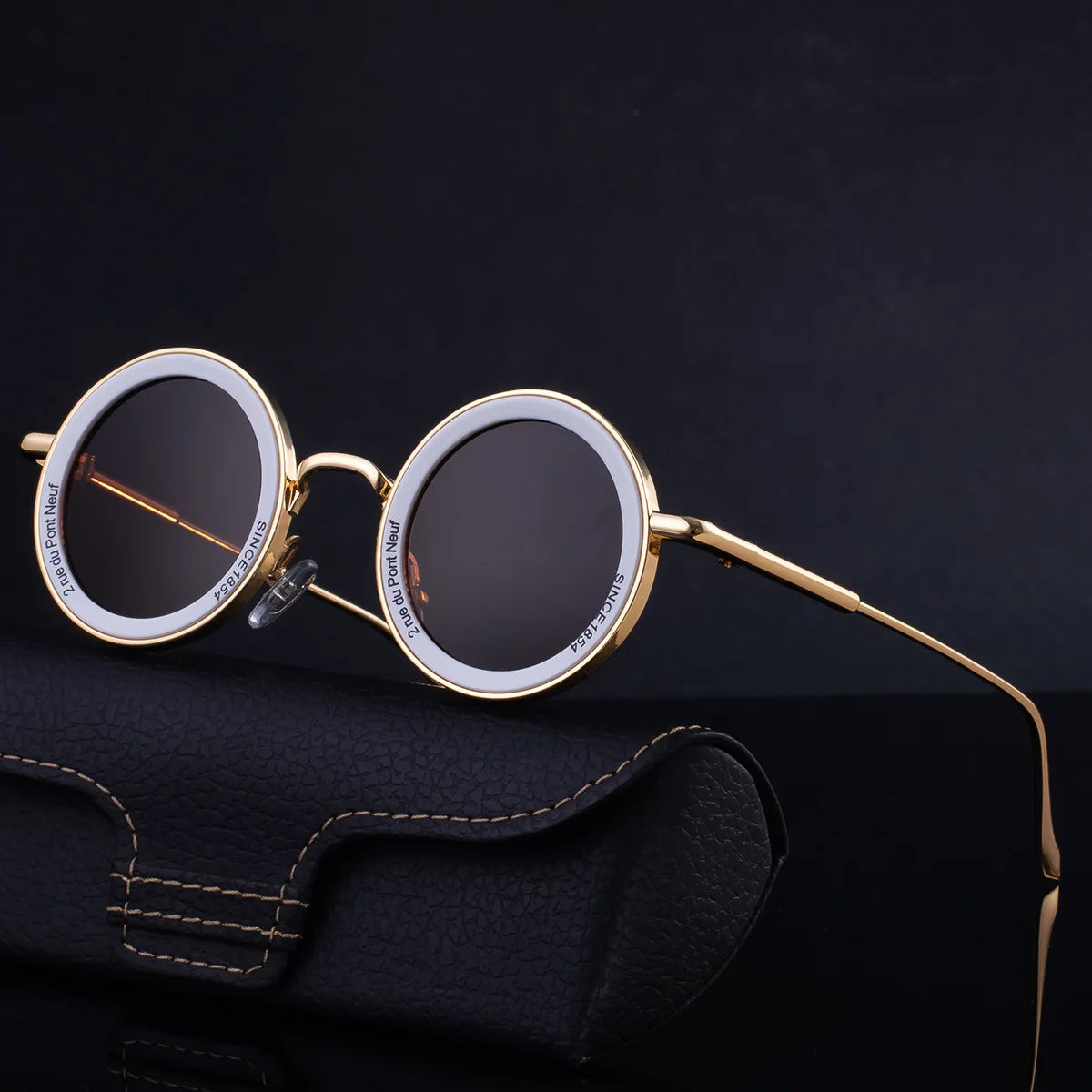 Round sunglasses with gold frame on a dark background