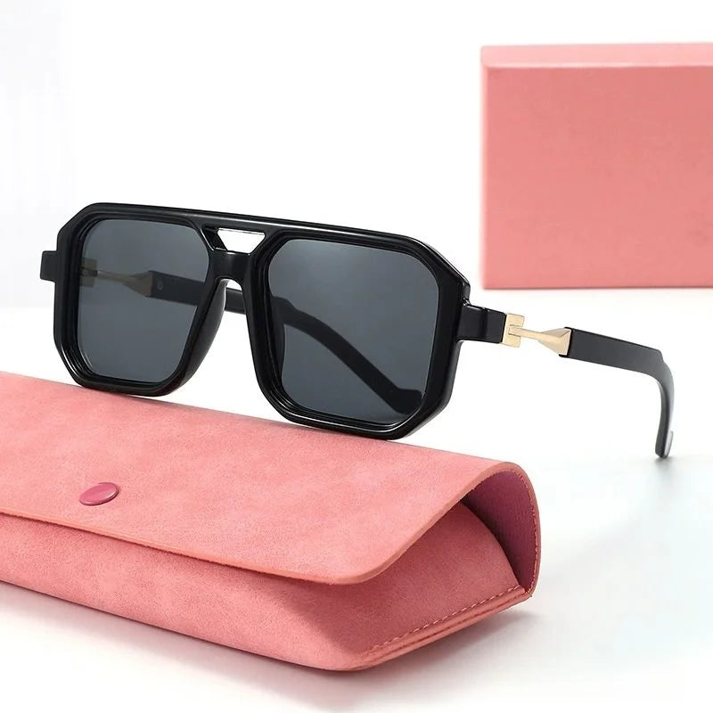 Black sunglasses with gold accents on a pink case against a white background