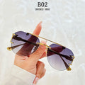 Sunglasses with gold frame and gradient lenses held by a hand against a light background
