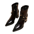 Pair of black leather boots with gold buckles on a white background