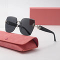 Sunglasses with decorative arms on a pink case and box against a light background