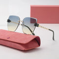 Sunglasses with gradient lenses and gold frame on a pink case with a matching box.