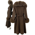 Brown coat with fur trim on a stand against a white wall
