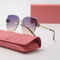 Sunglasses with gradient lenses and gold accents on a pink case with a matching box in the background.